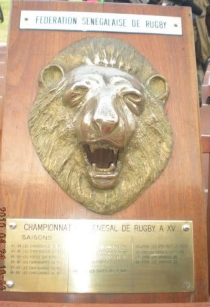 Le bouclier du Lion, trophée du championnat du Sénégal de rugby à XV : tête de lion en bronze sur socle en bois